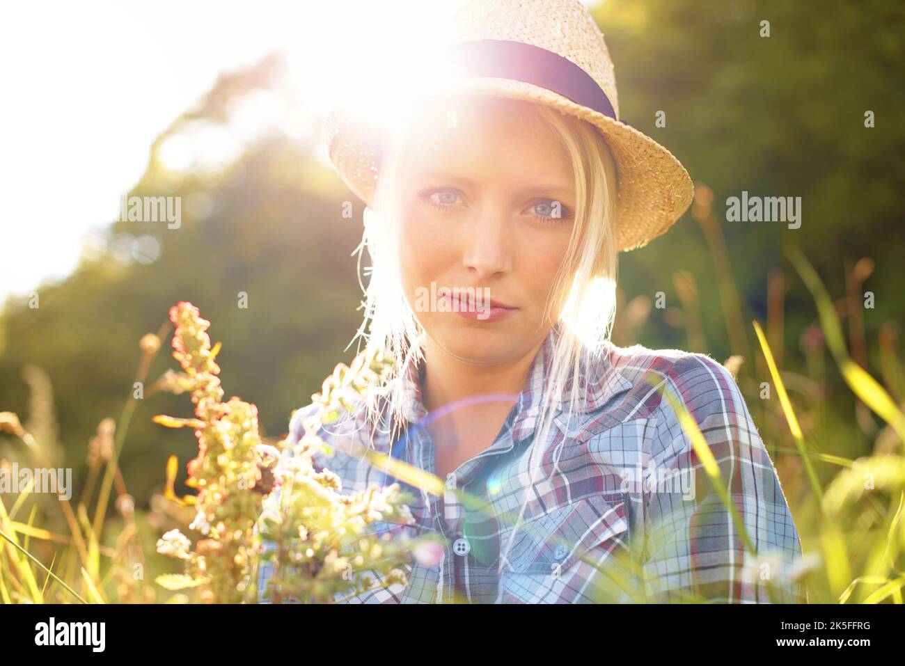 Sia il vostro proprio genere di bello. Bella giovane donna in un campo mentre indossa una fedora di paglia. Foto Stock