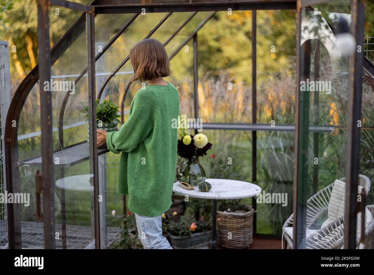 Donna con piante in serra Foto Stock