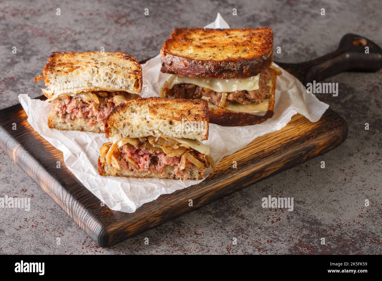 il patty melt è un panino composto da un polpettine di manzo macinato con formaggio fuso e sormontato con cipolle caramellate tra due fette di pane affumicato Foto Stock