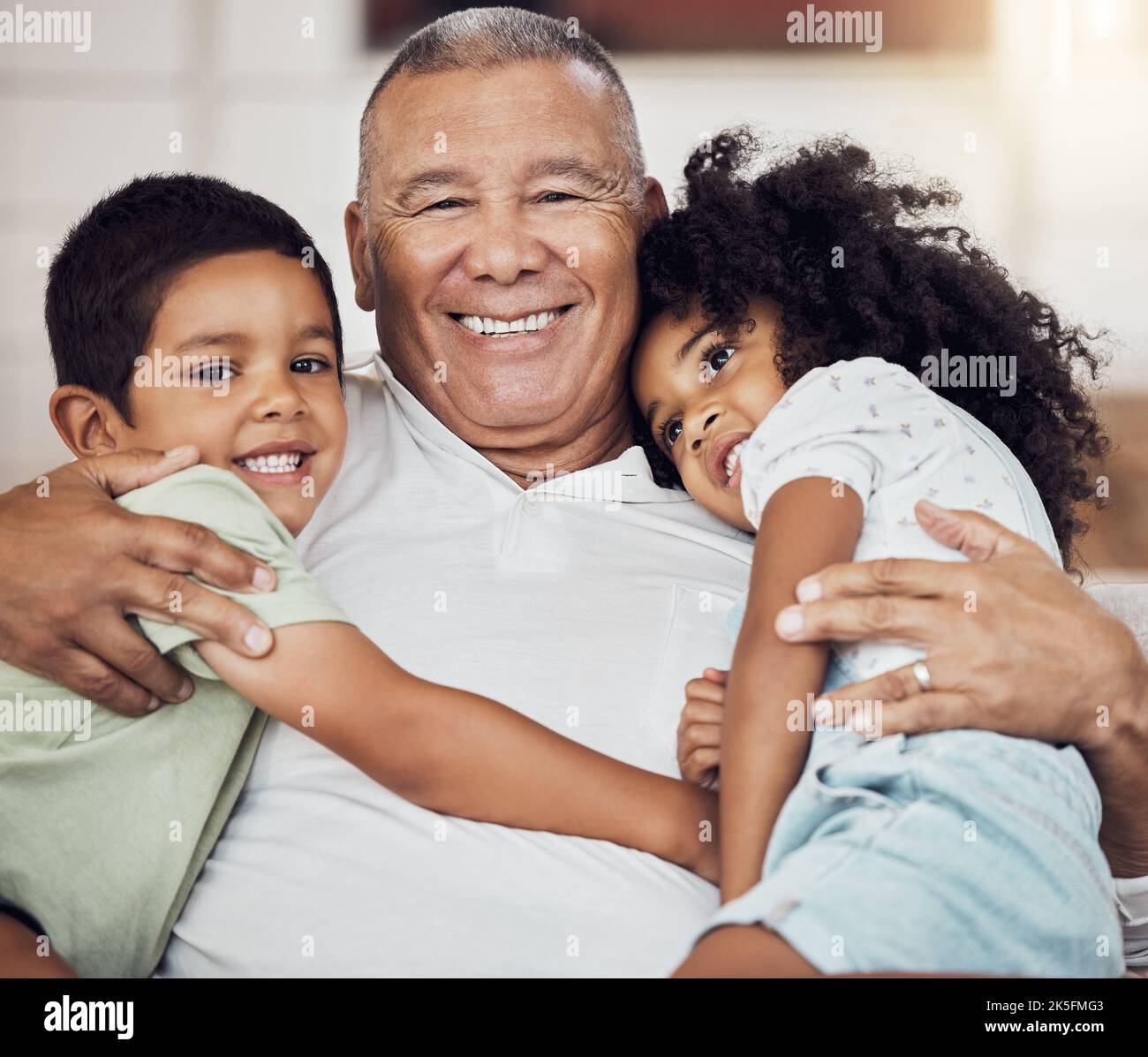 Ritratto, famiglia felice e nonno con i bambini nel soggiorno di casa abbracciando, rilassando e legandosi insieme. Anziani, felicità e anziani Foto Stock