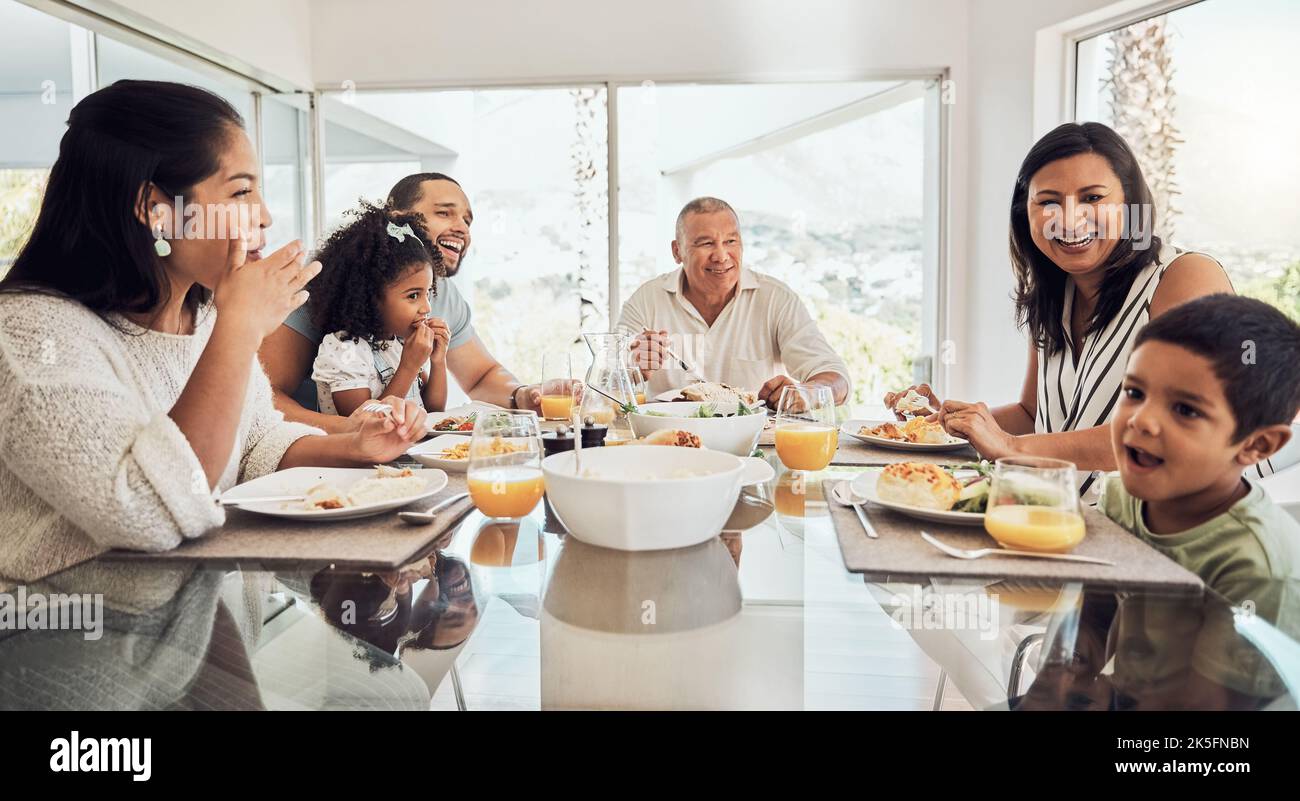 Buon cibo e colazione per tutta la famiglia al tavolo da pranzo a casa, chiacchierando, mangiando e legando. Nonni, genitori e bambini che si rilassano Foto Stock
