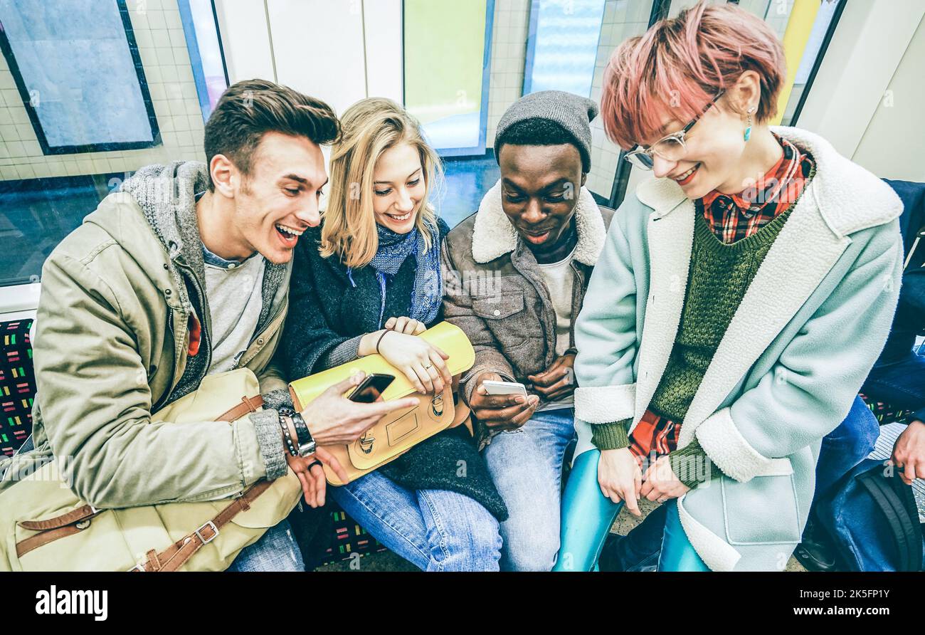 Gruppo di amici multirazziali hipster divertirsi in treno metropolitano - Urban concetto di amicizia con i giovani che guardano il telefono cellulare in città metropolitana Foto Stock