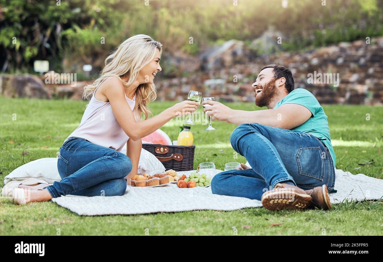 Coppia, pic-nic e parco di un uomo e una donna rallegrano per la felicità e l'amore nella natura. Gente felice insieme con un sorriso godendo l'alcool ed il cibo Foto Stock