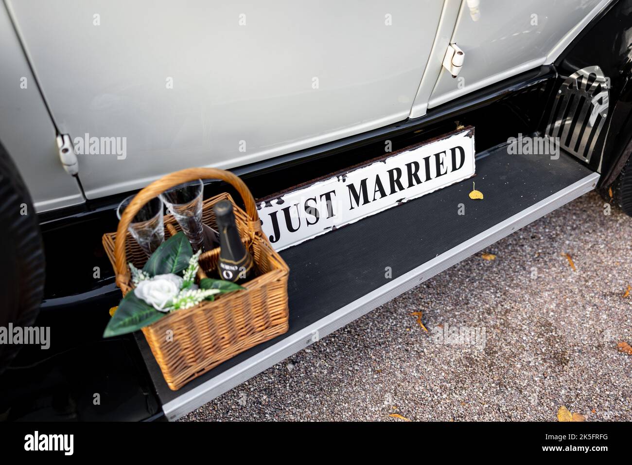 Segno appena sposato che riposa sull'automobile di cerimonia nuziale Foto Stock