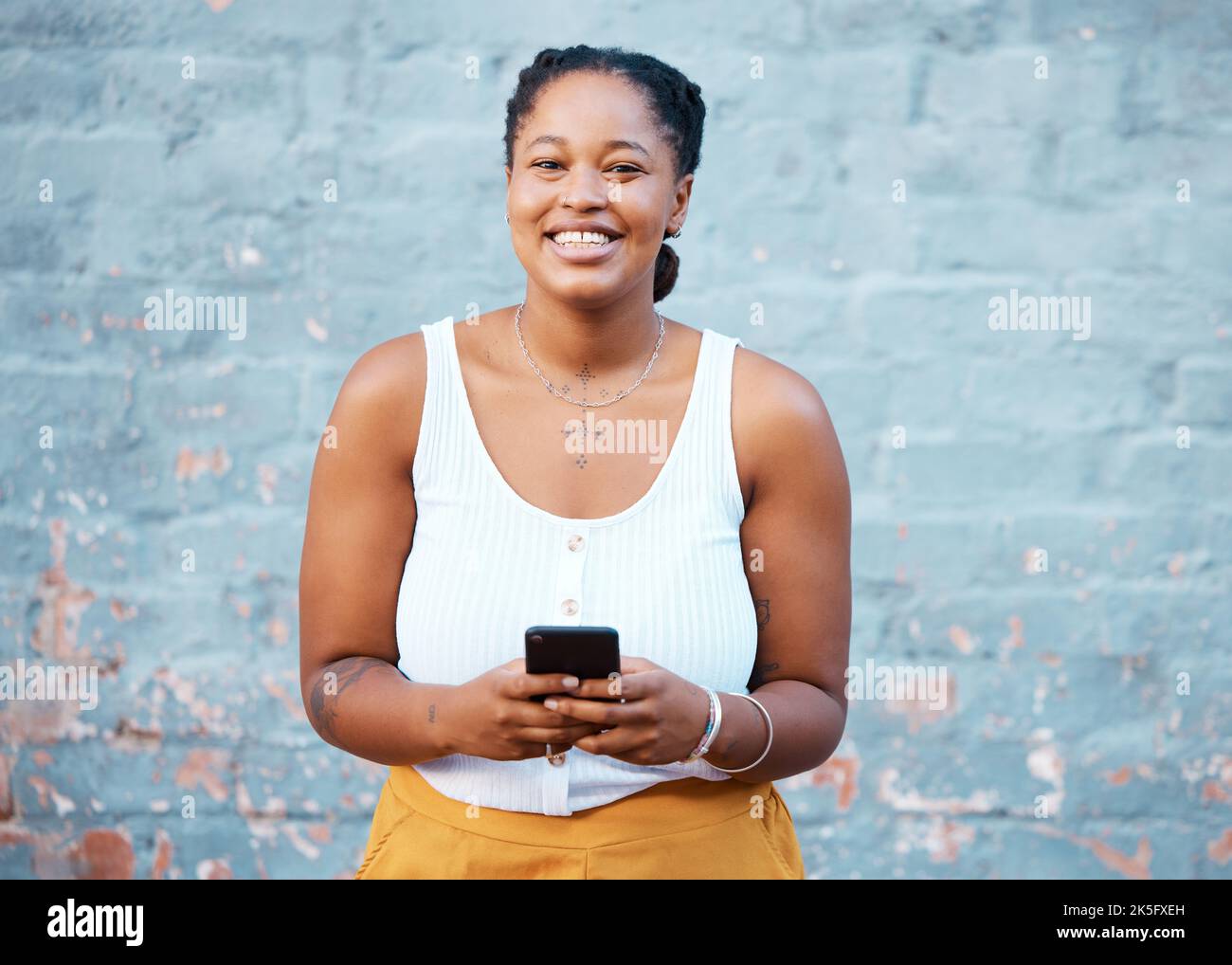 Smartphone, social media e donna nera con connettività di rete 5g, connessione a Internet o ricerca online su una parete blu mockup. Ragazza africana felice con Foto Stock