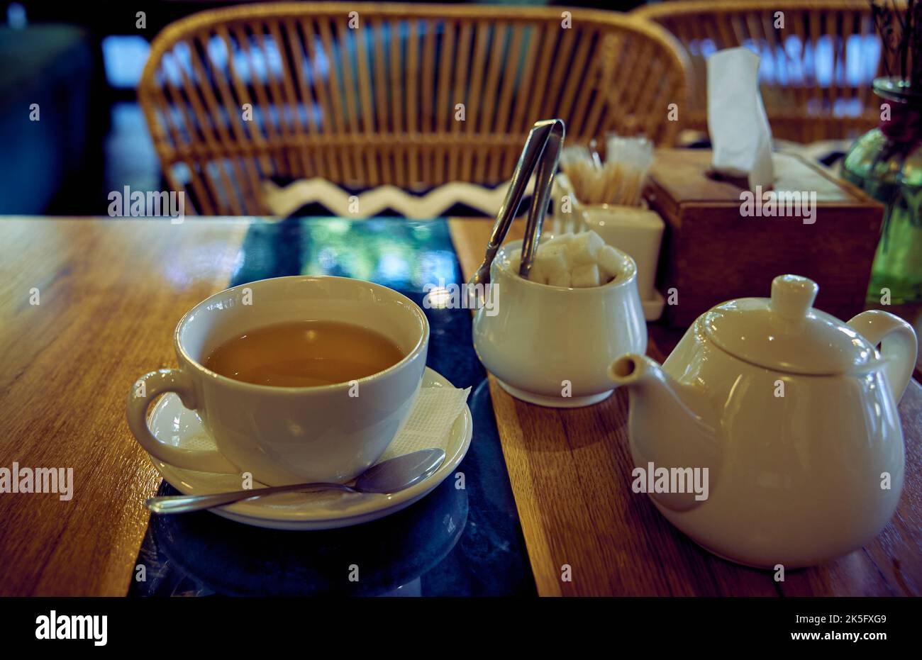 Set da tè in ceramica bianca. Tazza con tè verde, teiera e ciotola di zucchero al tavolo del ristorante Foto Stock