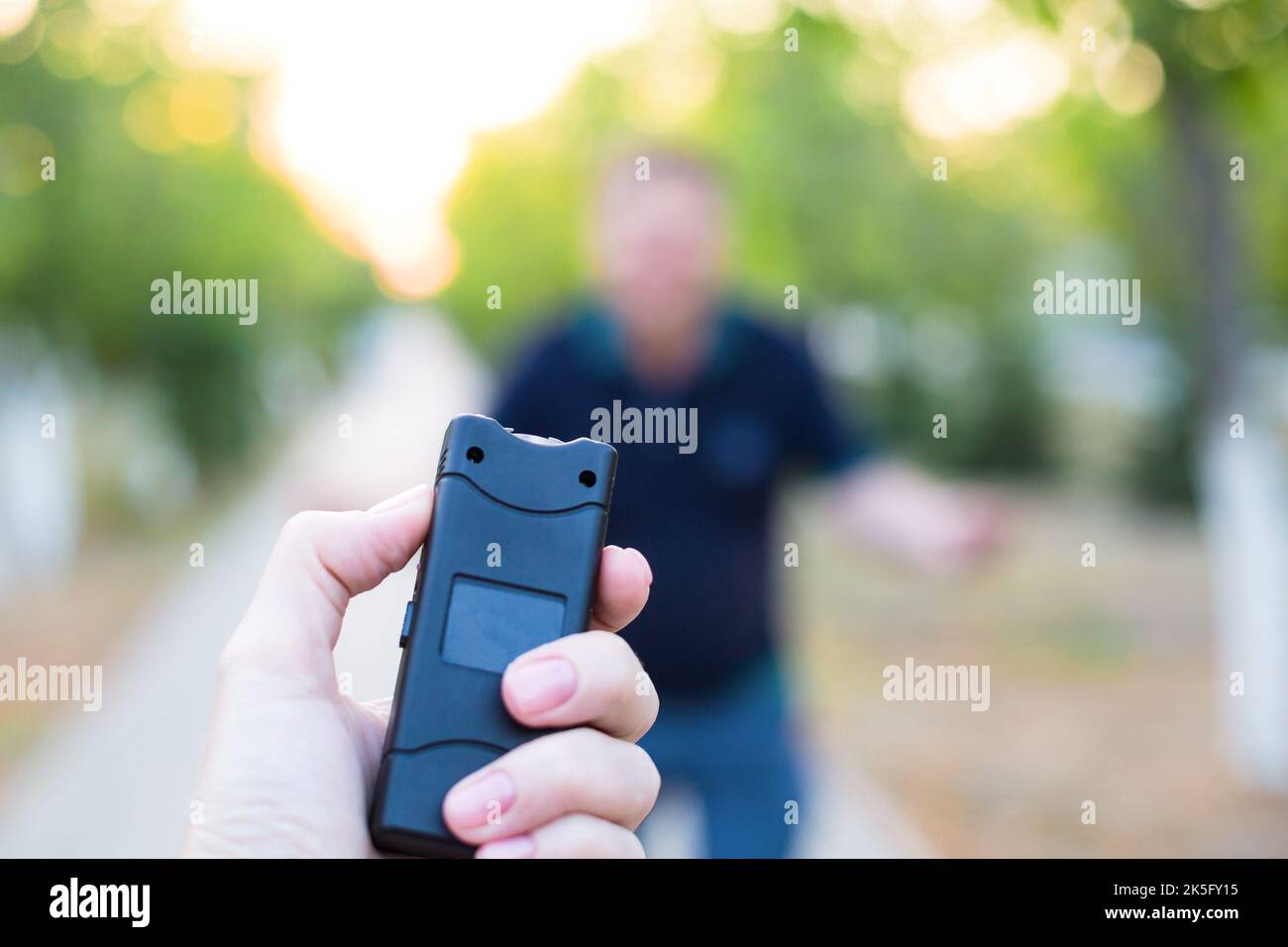 Una pistola mondana in mano a una donna, protezione da un uomo attaccante. Foto Stock