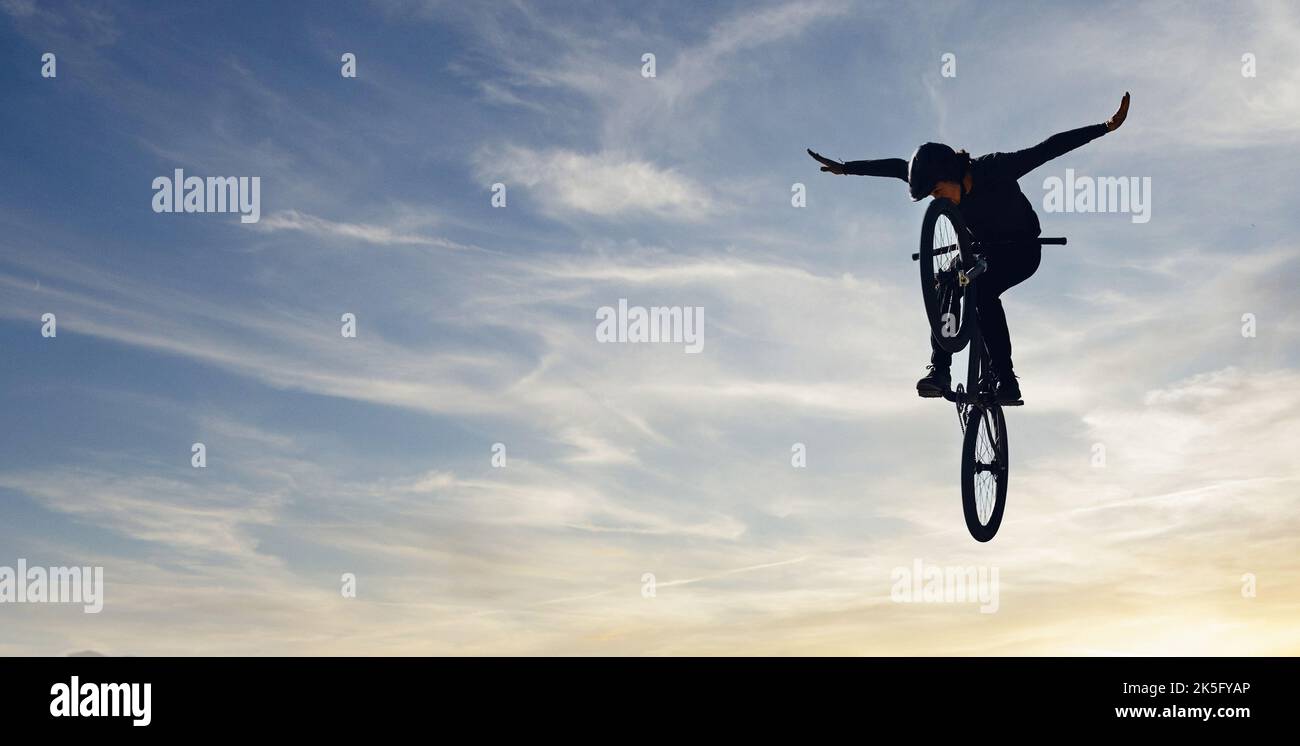 Mountain bike uomo, salto cielo e l'energia di azione, libertà e concorrenza silhouette, ombra e beffa. Atleta ciclistico professionista in aria, pericolo Foto Stock