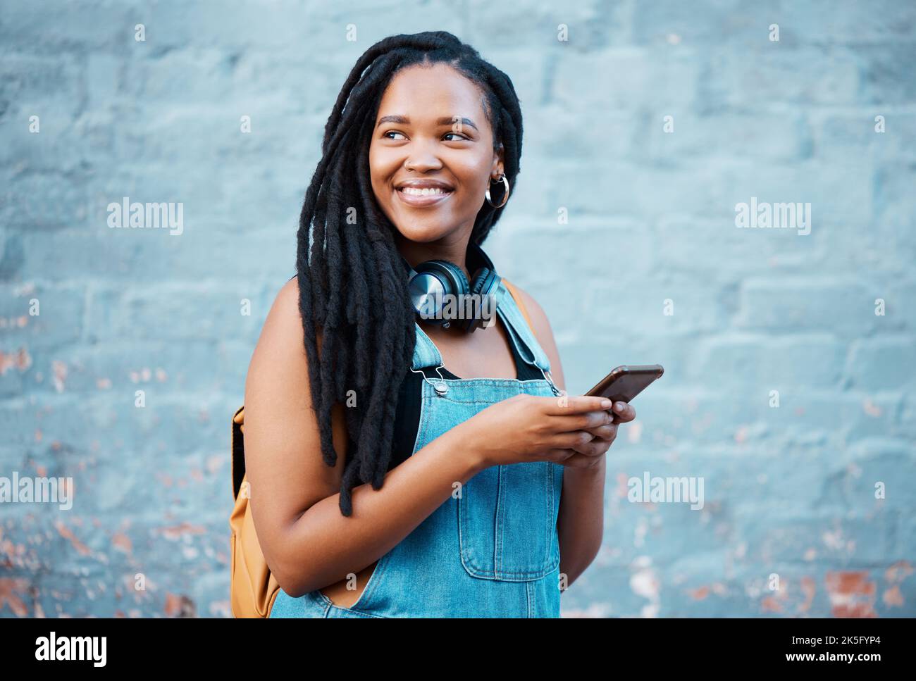 Social media telefono, cuffie per musica e donna nera pensando alla motivazione andare all'università in città. Studente universitario africano con visione per Foto Stock