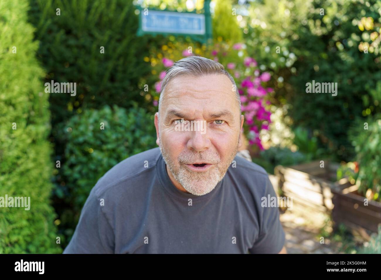 Uomo di mezza età che parla fissando con intelligenza la telecamera mentre si inclina in avanti con un'espressione seria Foto Stock