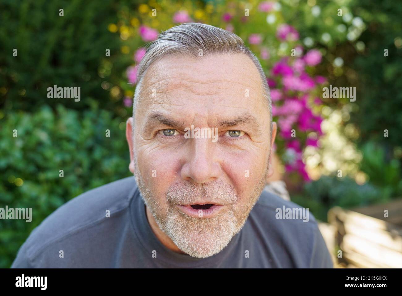 Uomo di mezza età che parla fissando con intelligenza la telecamera mentre si inclina in avanti con un'espressione seria Foto Stock