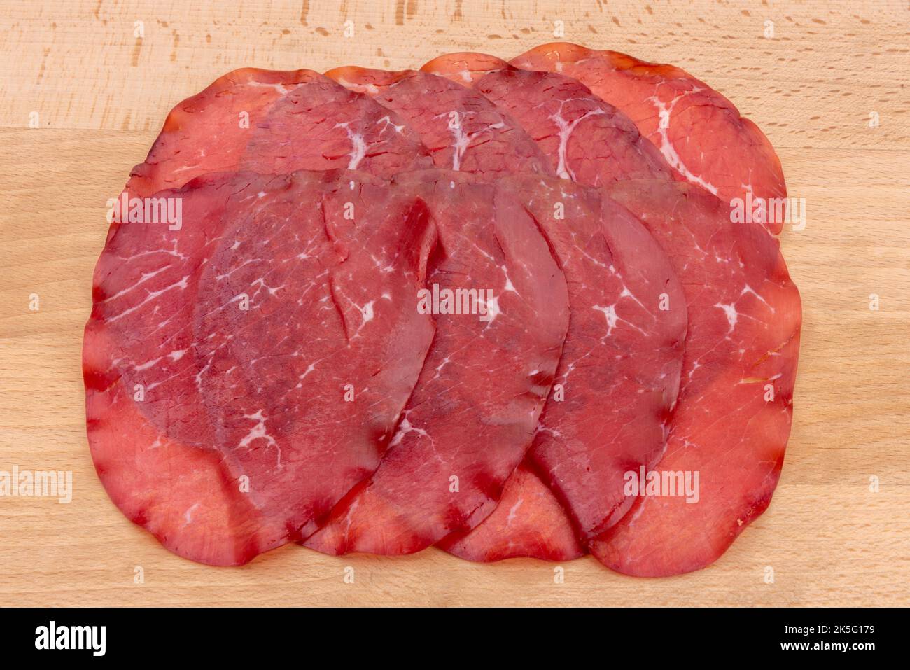 Fette di bresaola, salame di manzo italiano secco della Valtellina su fondo ligneo Foto Stock