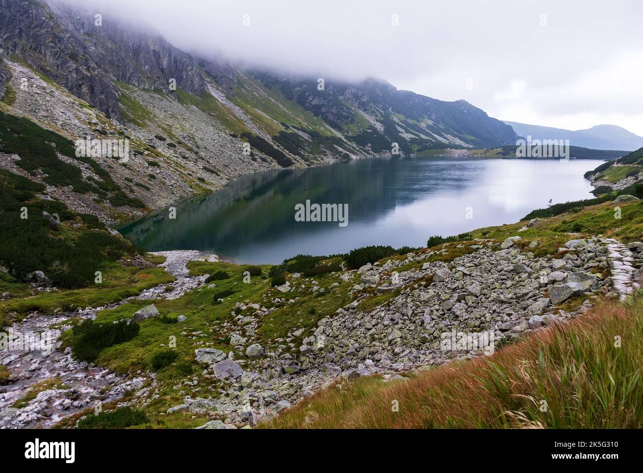 Una vista molto impressionante delle montagne polacche Tatra con molte rocce con un lago turchese incredibilmente bello nel mezzo delle montagne con la re Foto Stock