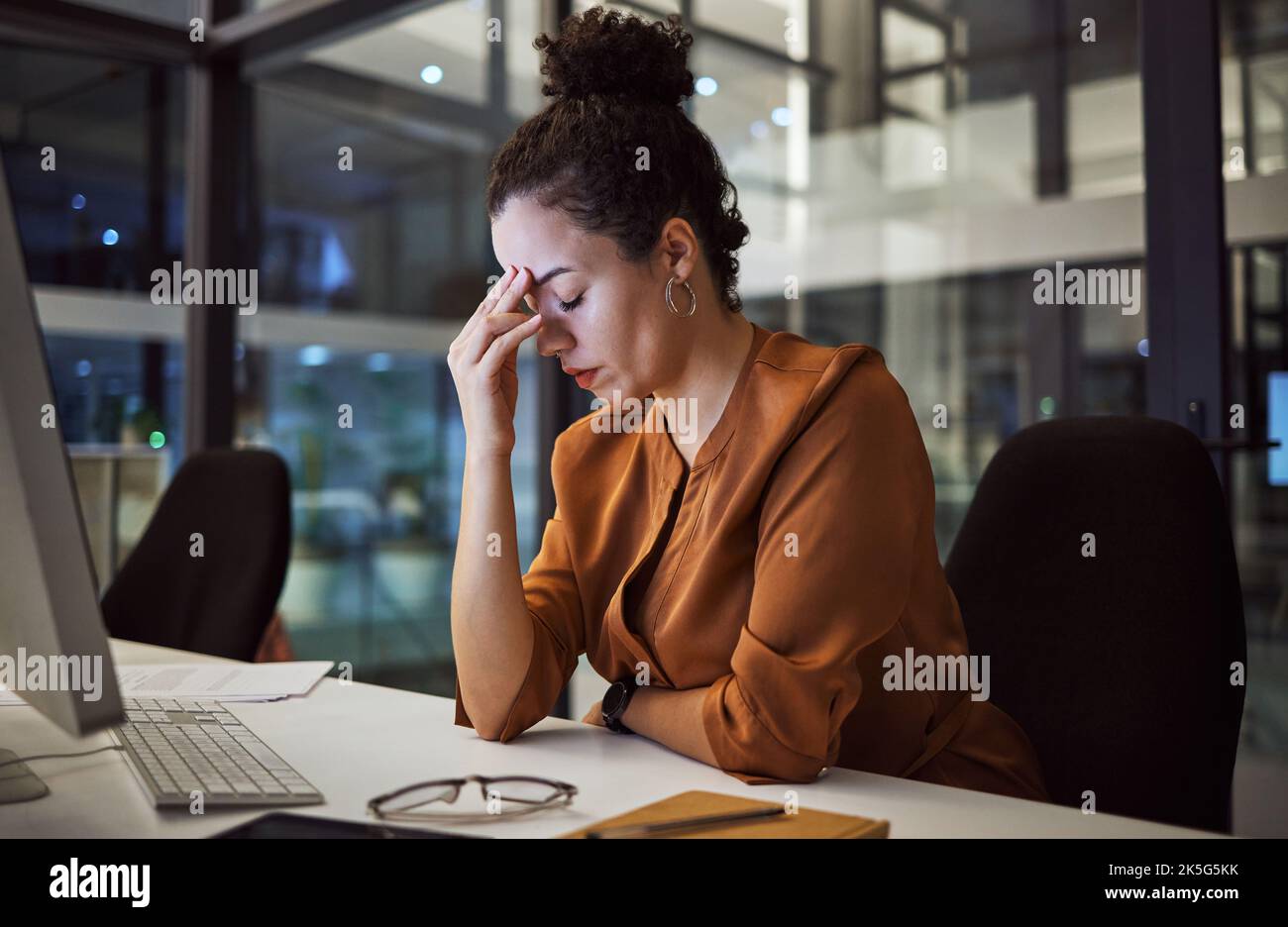 Donna che lavora di notte con mal di testa, burnout e stress sul progetto di social media marketing o sulla scadenza aziendale. Ansia, esausto e stanco web o. Foto Stock
