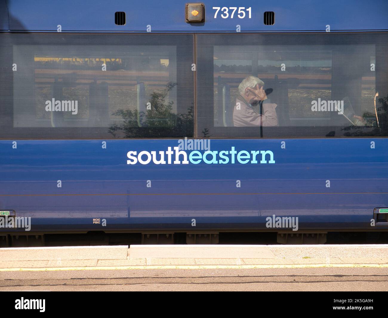 Il lato di una carrozza blu delle Ferrovie sud-orientali. Dietro una delle due finestre, i pendolari si siedono in attesa che il treno continui il suo viaggio. Foto Stock