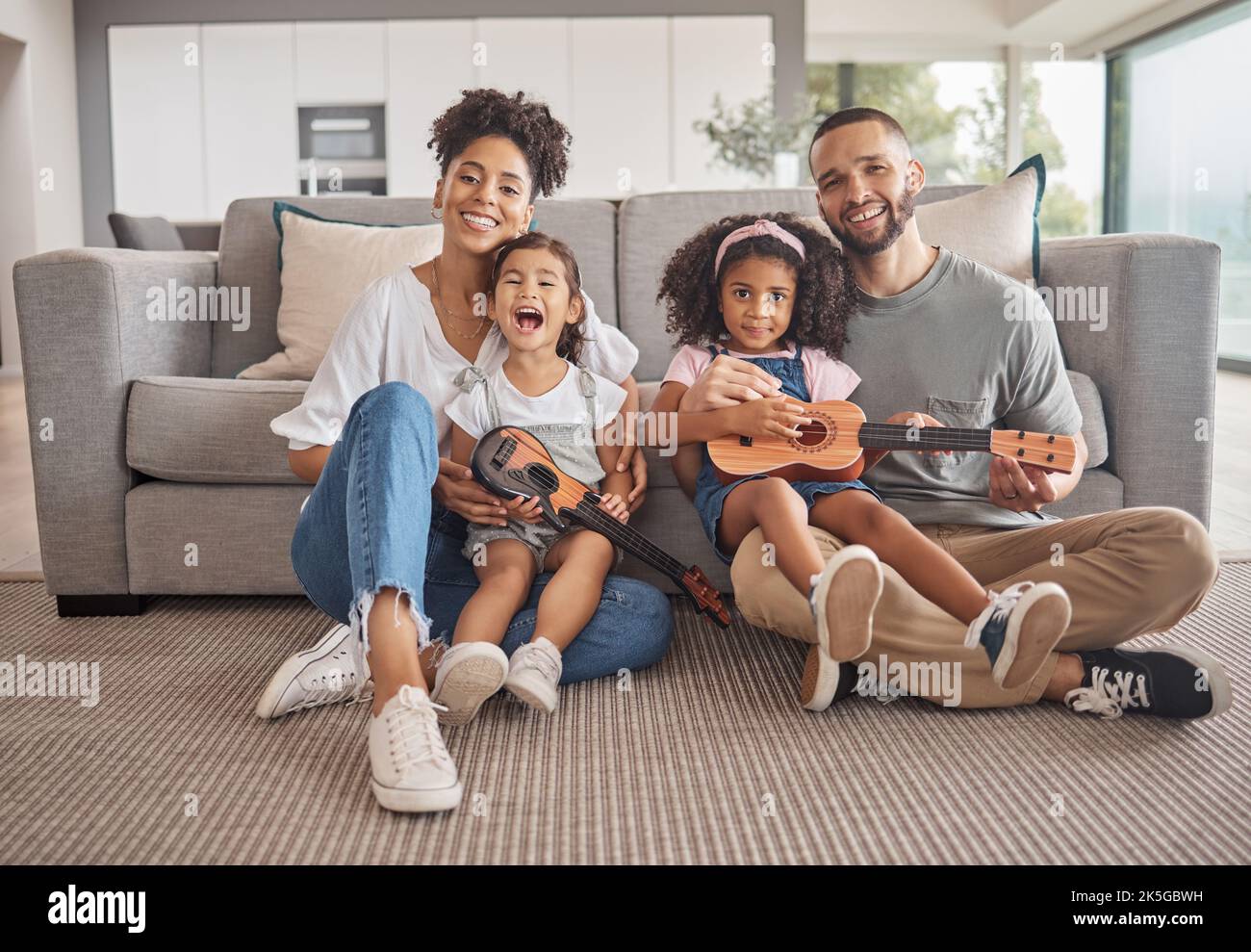 Famiglia, bambini e musica con una ragazza e chitarra in un soggiorno con genitori e sorella a casa. Bambini, felici e innamorati di una madre, padre e. Foto Stock