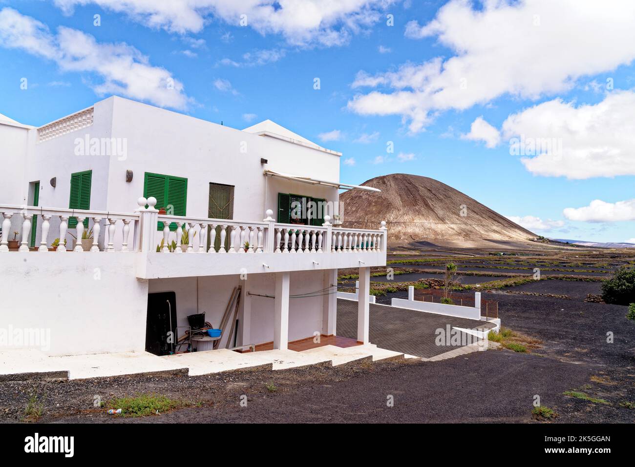 Tipica casa colonica bianca delle Canarie sull'isola di Lanzarote a Mancha Blanca con crateri vulcanici sullo sfondo in un soleggiato pomeriggio invernale. Lanzarote è Foto Stock