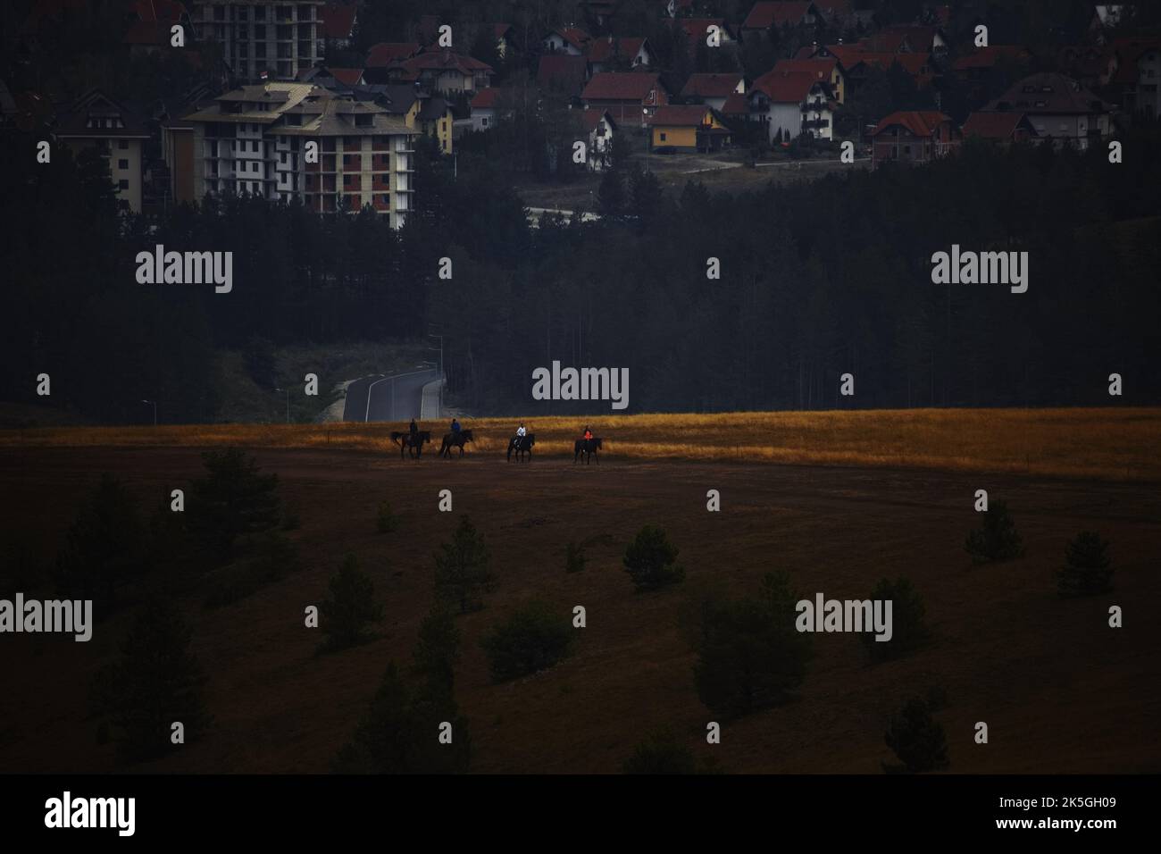 Un bellissimo paesaggio rurale con cavalieri nel campo al tramonto Foto Stock