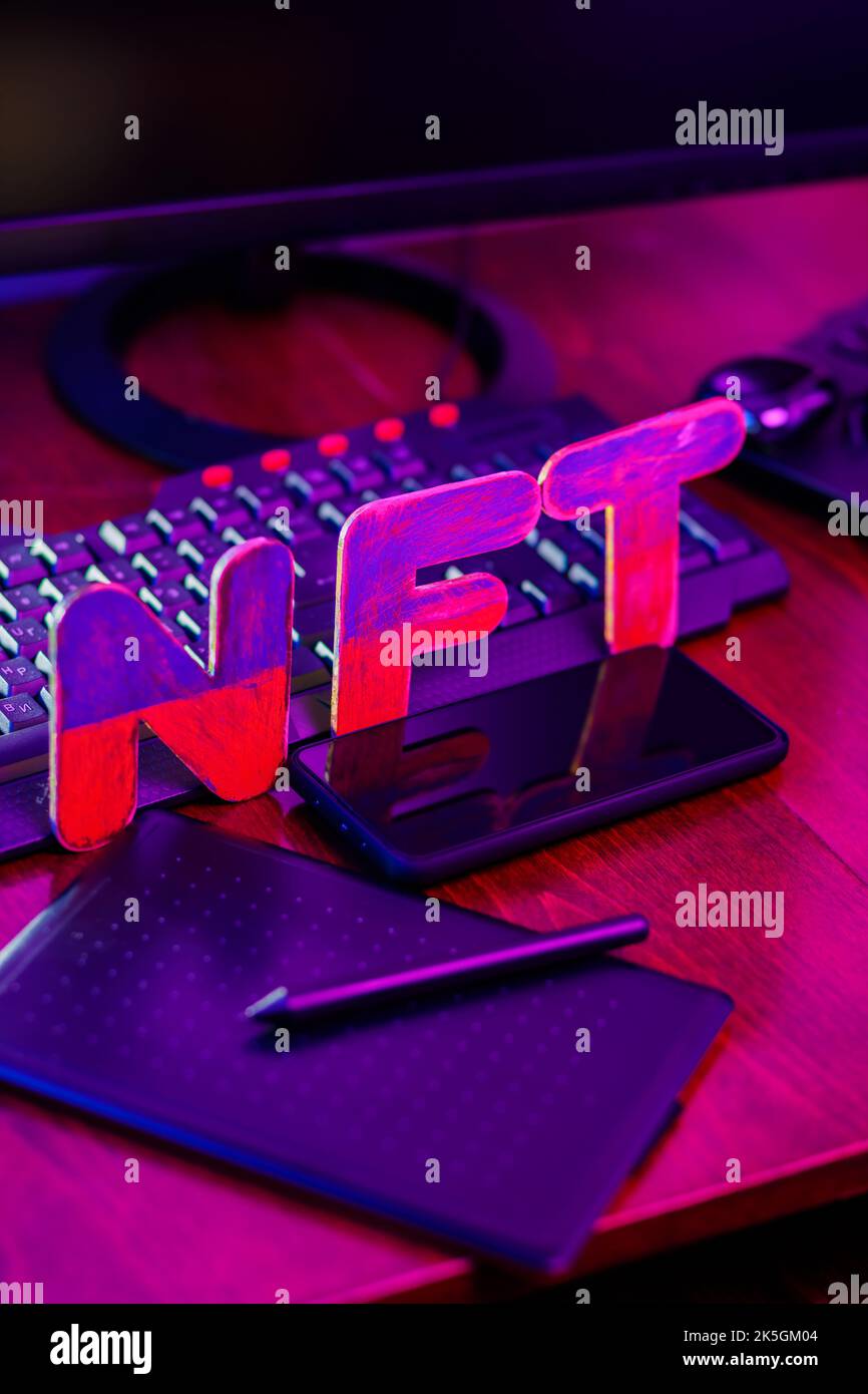 Creazione di NFT da parte di un artista digitale in un ufficio domestico. Scritte NFT sul posto di lavoro con tablet grafico, penna, smartphone e computer. Arte cripto Foto Stock