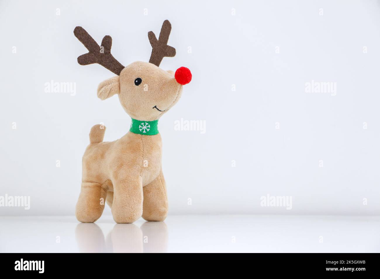 Rudolph il giocattolo molle delle renne dal naso rosso sorridente su sfondo bianco innevato, concetto di Natale Foto Stock