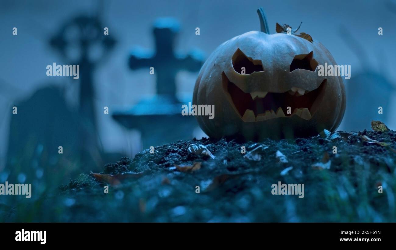 Zucca di Halloween scura tra le tombe del cimitero. Evento di festa Halloween concetto. Foto Stock