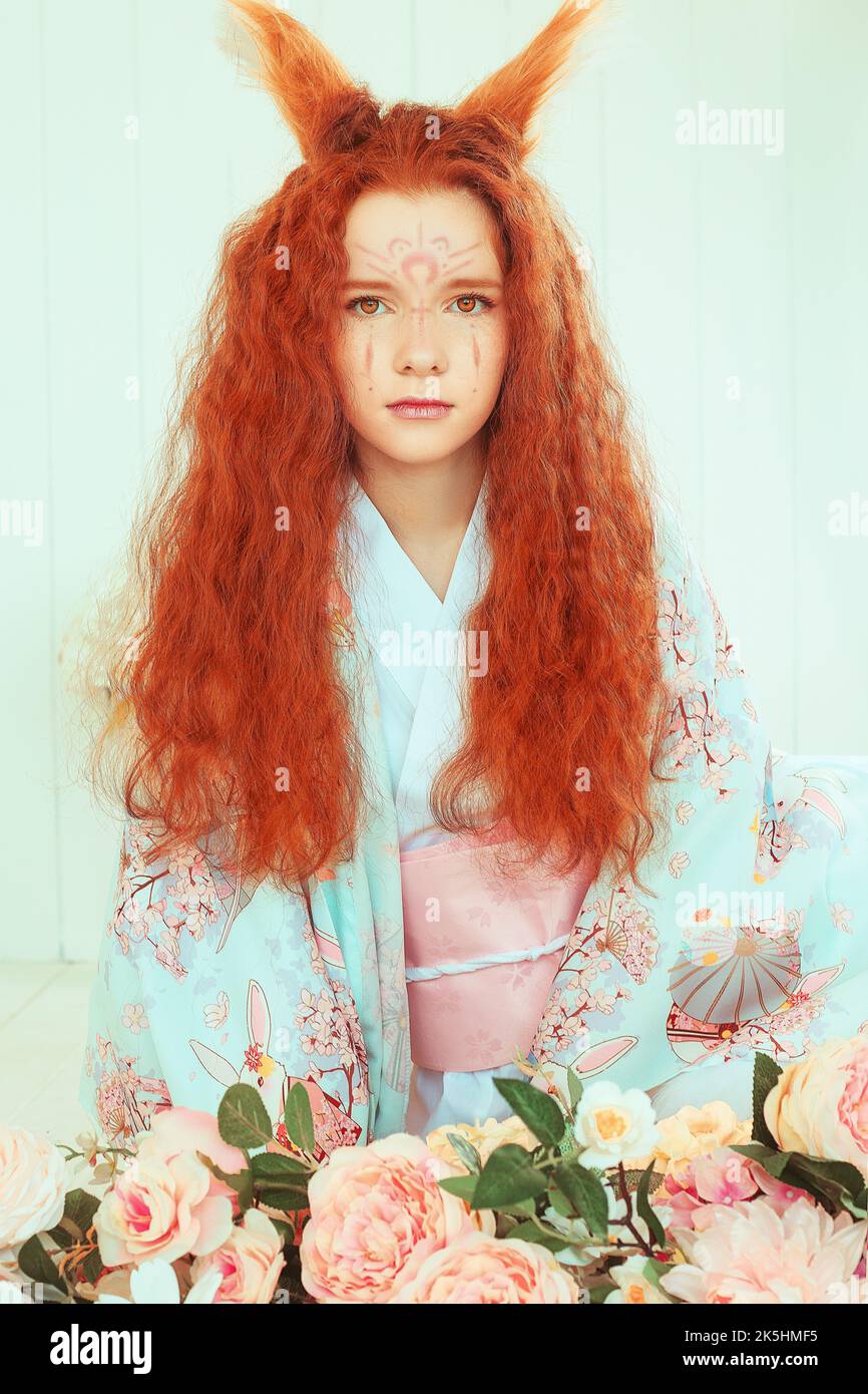 giovane ragazza dai capelli rossi con orecchie e code volpe. Nove volpe a coda. Ragazza giovane in kimono Foto Stock