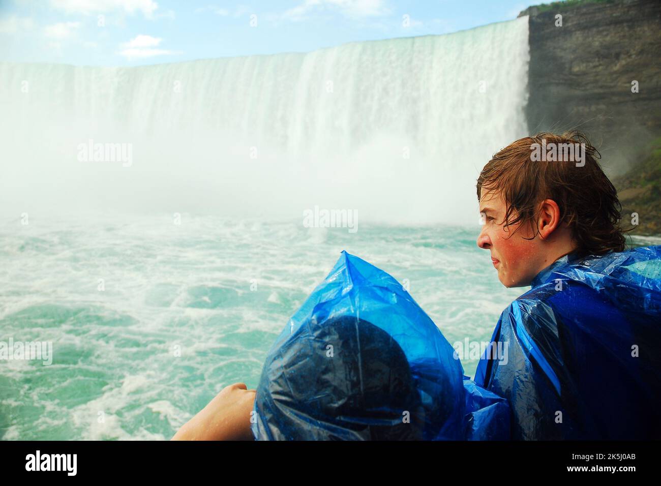 I bambini che fanno il tour in barca Maid of the Mist alle Cascate del Niagara si ubriacano mentre si trovano vicino alle Cascate canadesi Horseshoe, nonostante i loro poncho blu Foto Stock
