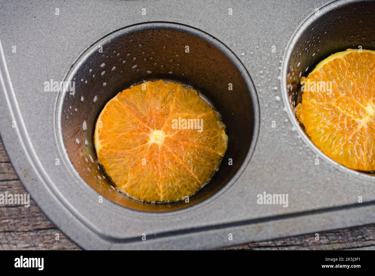 Muffola antiaderente rivestita con fette di Cara Cara Orange: Padella di muffin unta con sottili fette di arancia in ogni tazza Foto Stock