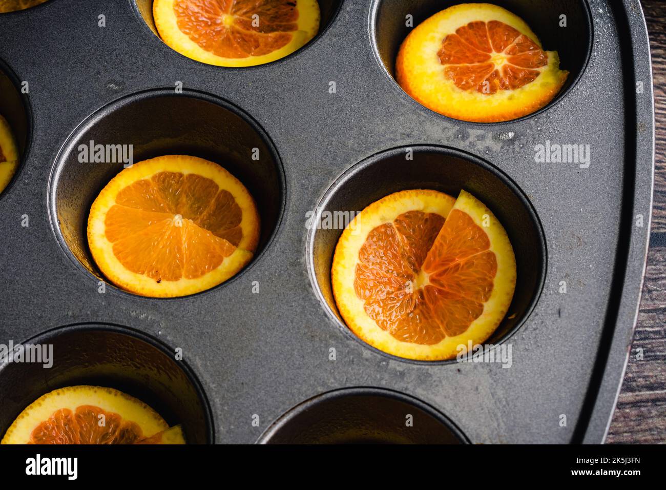Muffola antiaderente rivestita con fette di Cara Cara Orange: Padella di muffin unta con sottili fette di arancia in ogni tazza Foto Stock