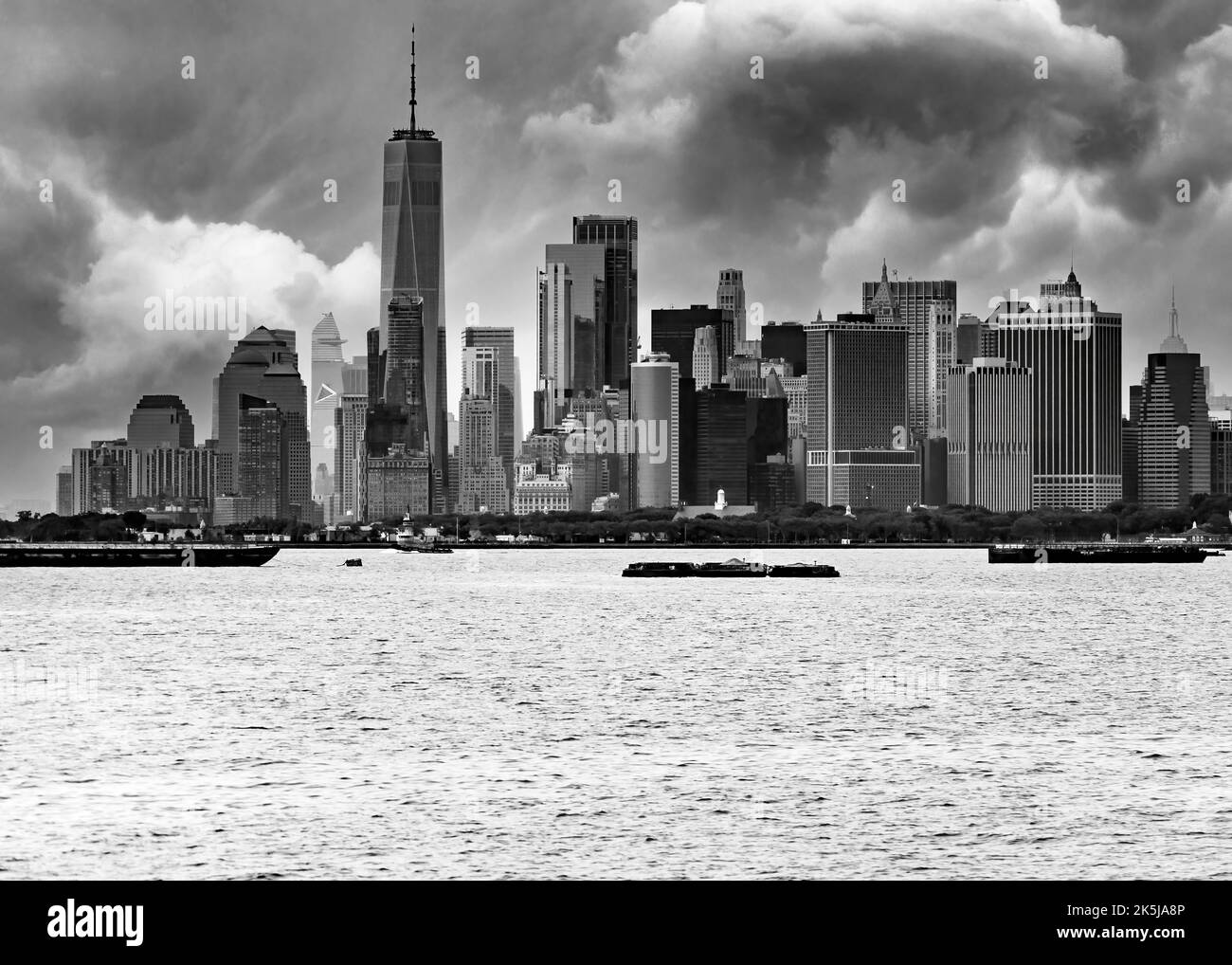 Skyline del centro di Manhattan con cielo sporco sullo sfondo e porto e fiume in primo piano in bianco e nero Foto Stock