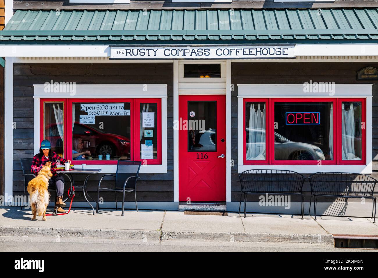 Turista e cane seduti fuori dalla Rusty Compass Coffeehouse; Haines; Alaska; USA Foto Stock
