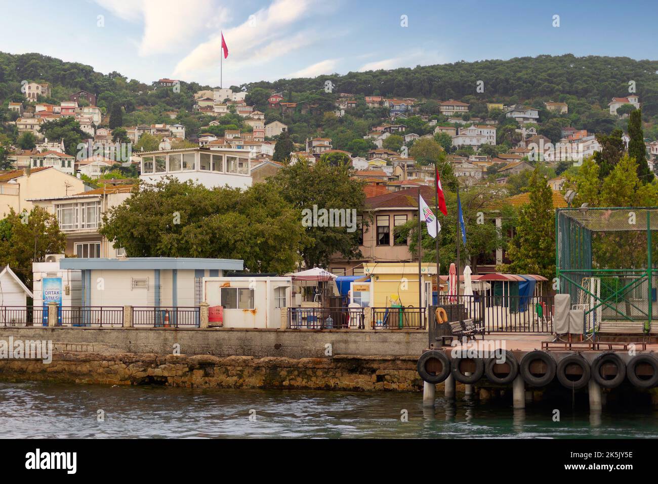 Istanbul, Turchia - 25 agosto 2022: Mare di Marmara, terminal dei traghetti dell'isola di Kinaliada con case estive e montagne verdi sullo sfondo Foto Stock