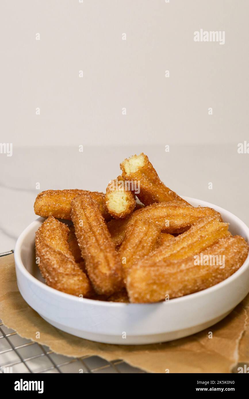 primo piano dei churros con lo zucchero nel recipiente bianco, vista dall'alto Foto Stock