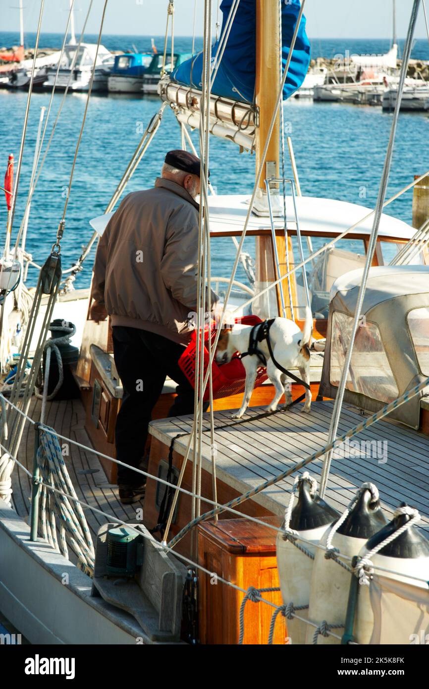 Compagni che si preparano per un altro viaggio. Un uomo anziano e il suo cane in piedi in una barca stipata. Foto Stock