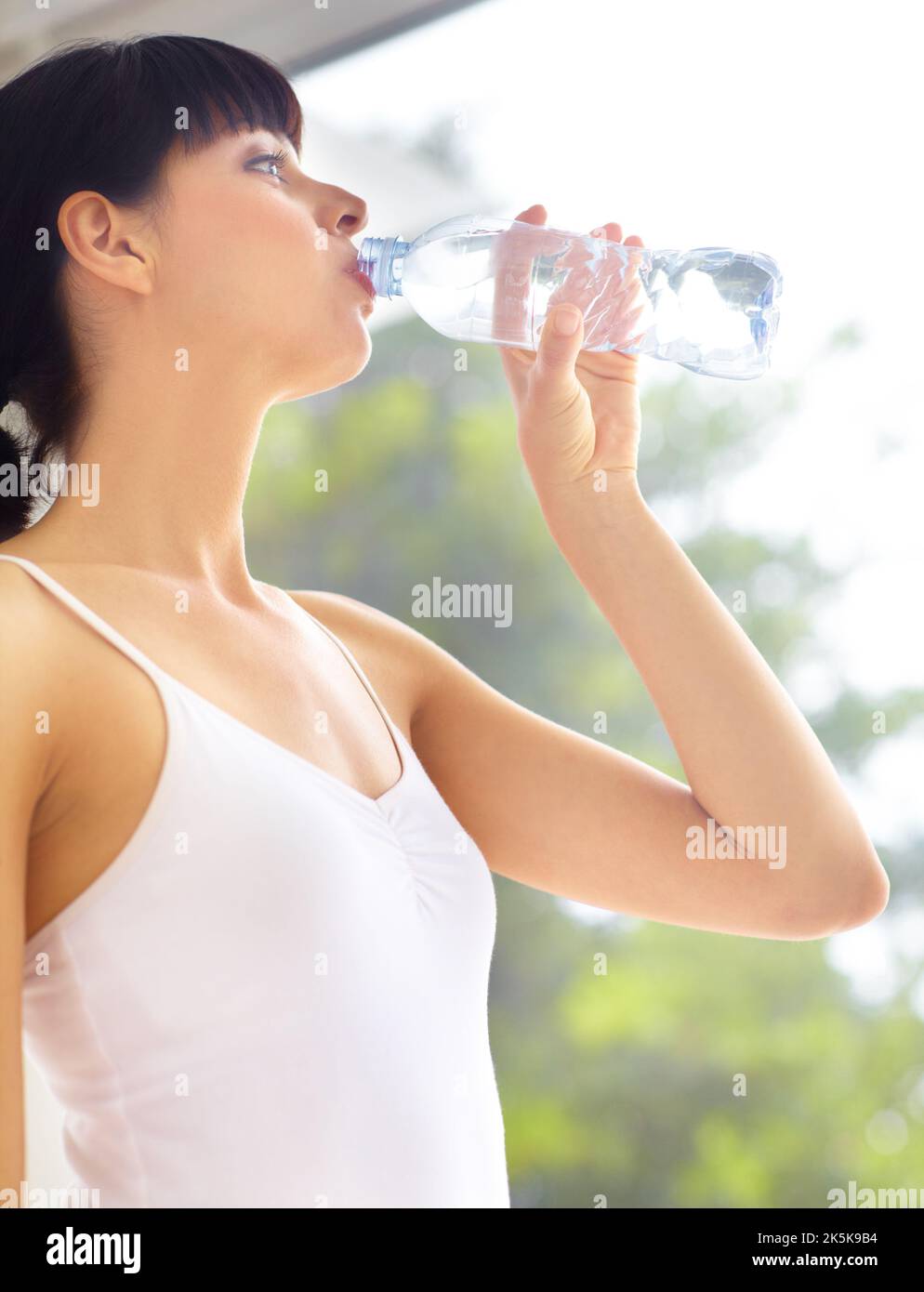 Acque grandi per il suo benessere. Bella giovane donna in attrezzatura fitness bere acqua da una bottiglia. Foto Stock