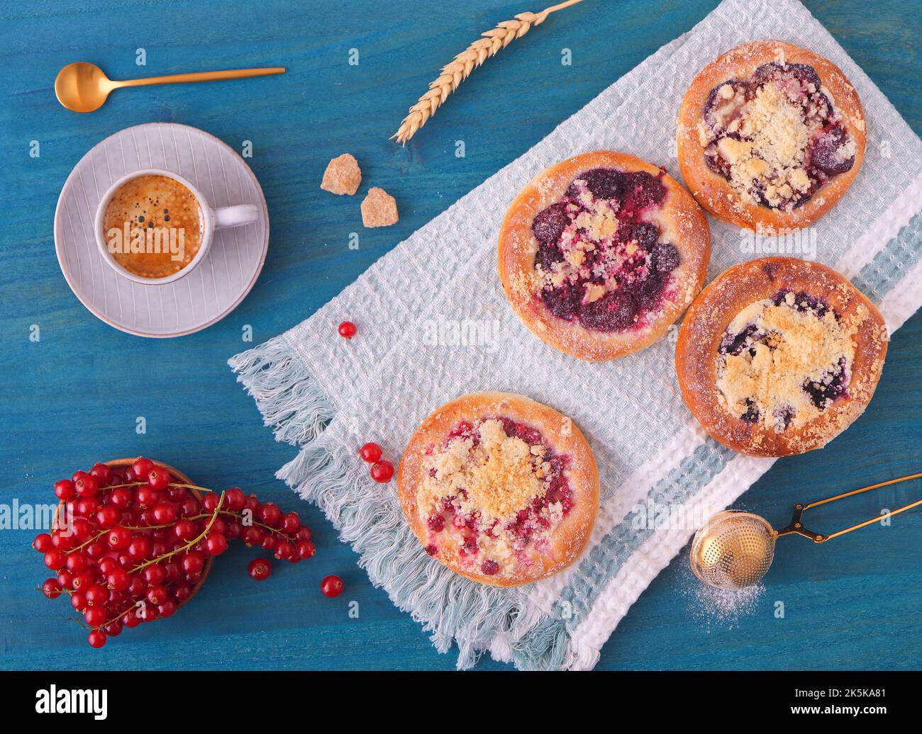 Primo piano di torte farcite di frutti estivi, ribes, prugne, more, mirtilli e crumble, tavolo in legno blu, angolo di visuale alto, piano, t Foto Stock