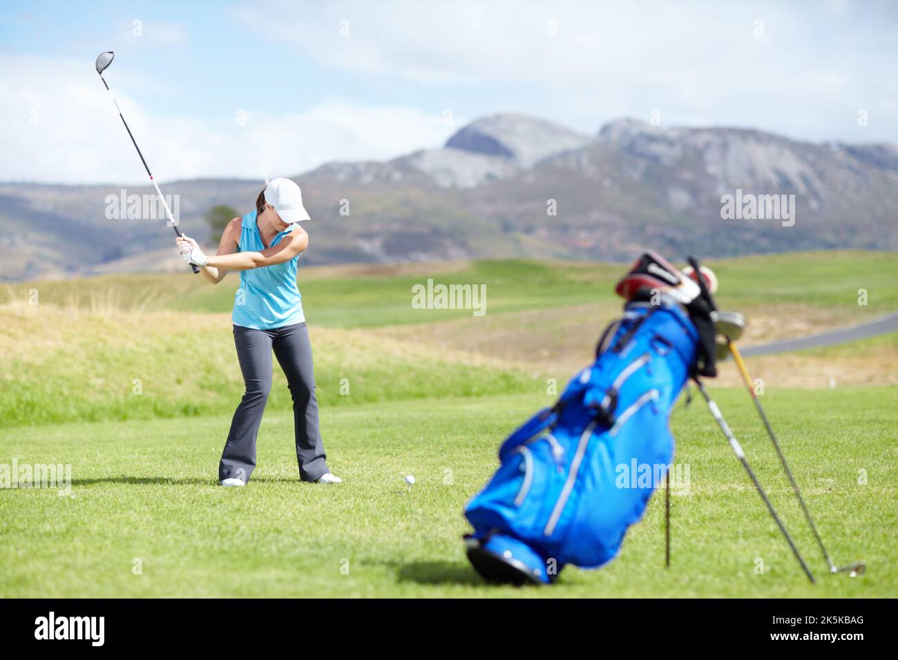 Esecuzione del taglio. Una golfista femminile che sta per prendere un colpo con una borsa da golf sfocata in piedi in primo piano. Foto Stock