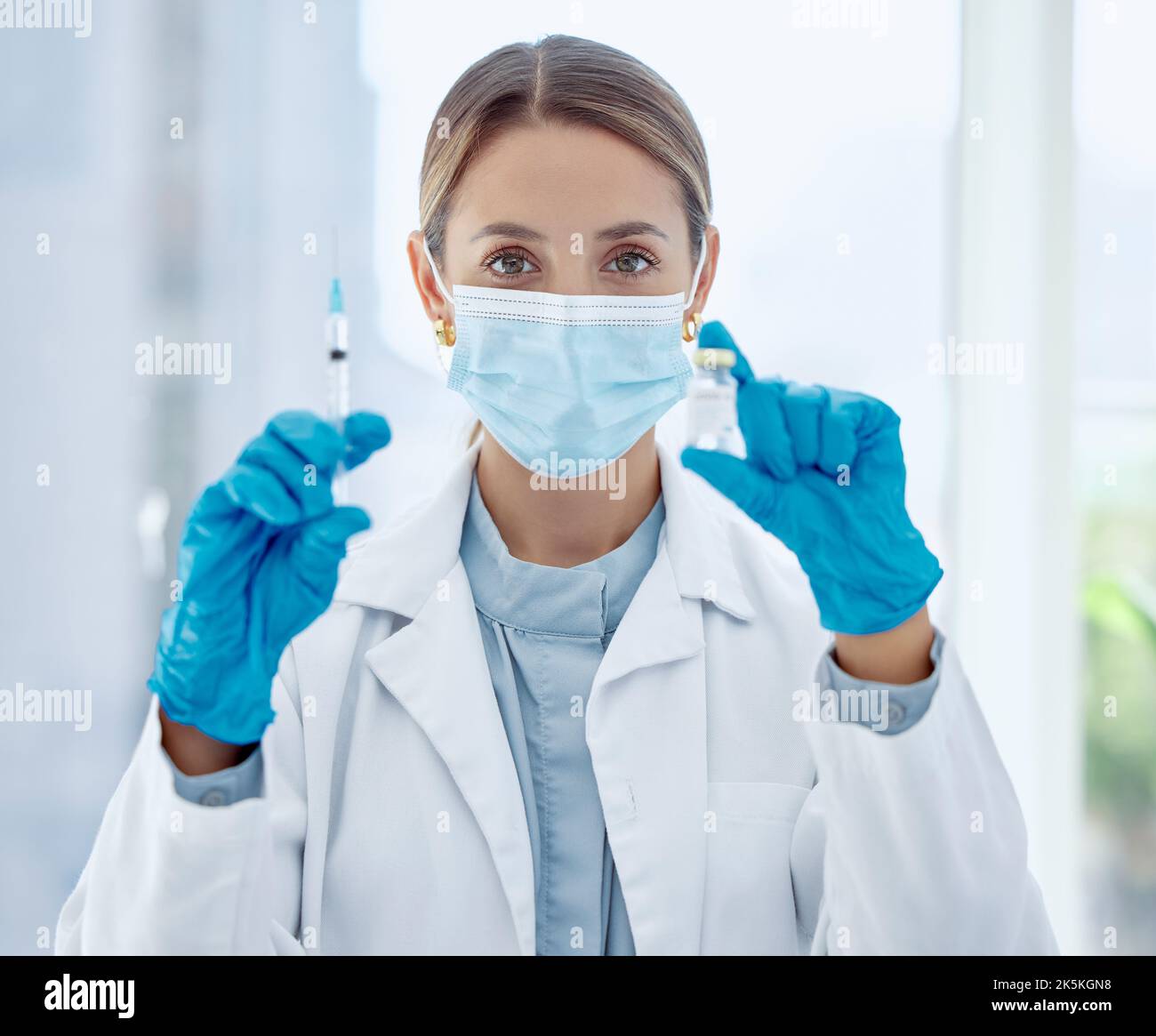 Medico, maschera e ago con vaccino per il covid in bottiglia in ospedale, per la salute e la sicurezza della comunità. Donna, medica e iniezione in laboratorio per la ricerca Foto Stock