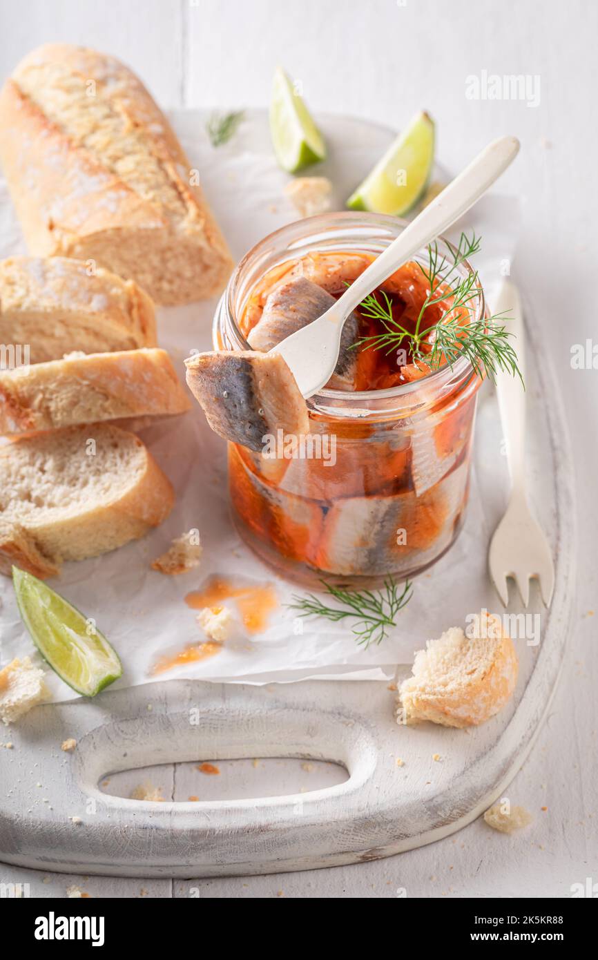 Pesce marinato fresco e delizioso come fonte di grassi sani. Aringa in vaso servita con pane. Foto Stock