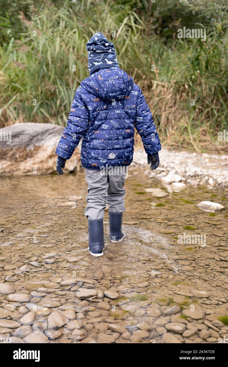 Un ragazzo si trova sulla riva del fiume durante l'alluvione primaverile Foto Stock