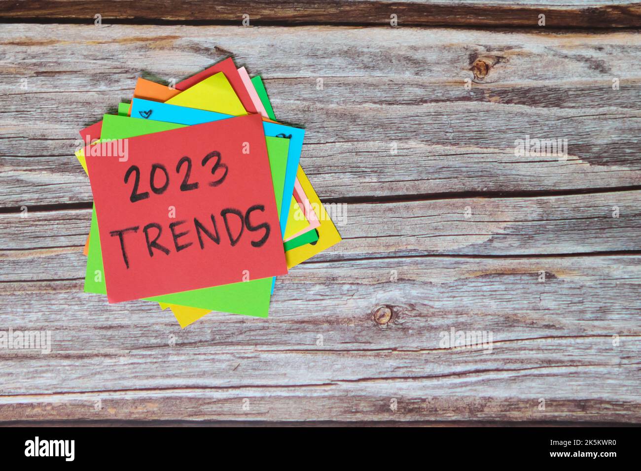 Nuovo anno 2023 nuovo concetto di trend. Note colorate appiccicose su sfondo di legno. Foto Stock