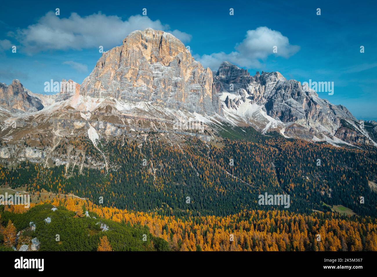 Pittoresco scenario alpino autunnale con variopinte foreste di larici sulle pendici e le alte montagne sullo sfondo, Dolomiti, Italia, Europa Foto Stock