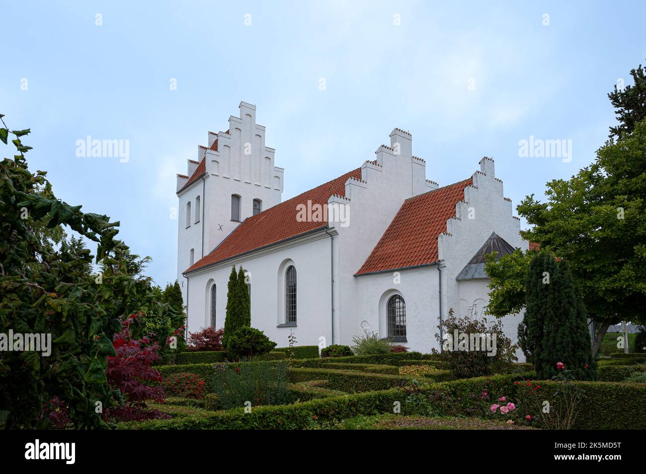 Bianca chiesa scandinava con una torre e scuderie a gradini a Kirke Hyllinge, Danimarca, Oktober 4, 2022 Foto Stock