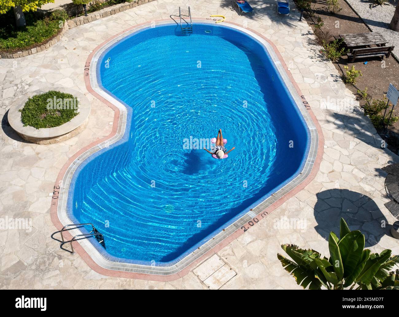 Vista dall'alto di una donna che si rilassa su un letto ad aria in una piscina, Paphos, Cipro Foto Stock