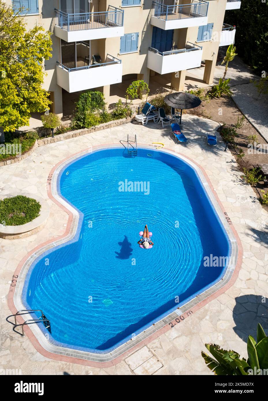 Vista dall'alto di una donna che si rilassa su un letto ad aria in una piscina, Paphos, Cipro Foto Stock
