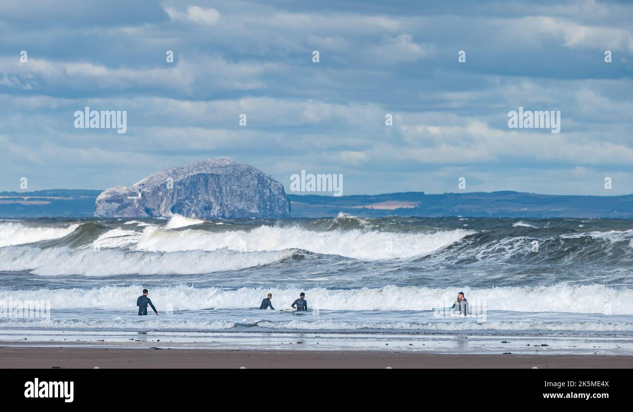 Surfers nel Firth of Forth in una giornata ventosa con grandi onde con l'isola di Bass Rock in lontananza, Scozia, Regno Unito Foto Stock