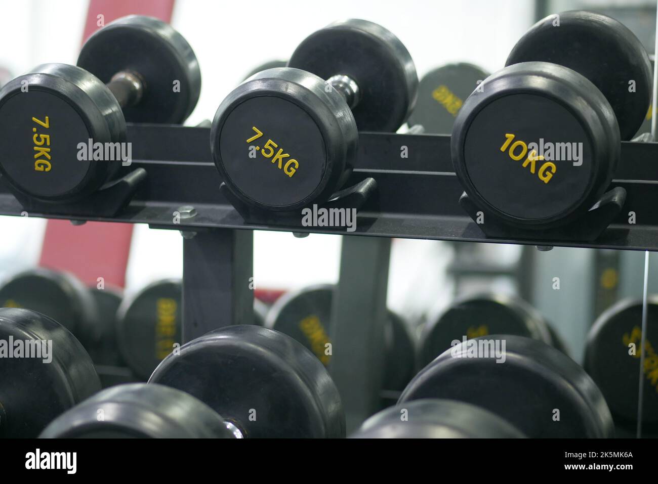 File di manubri di colore nero con numeri in palestra Foto Stock