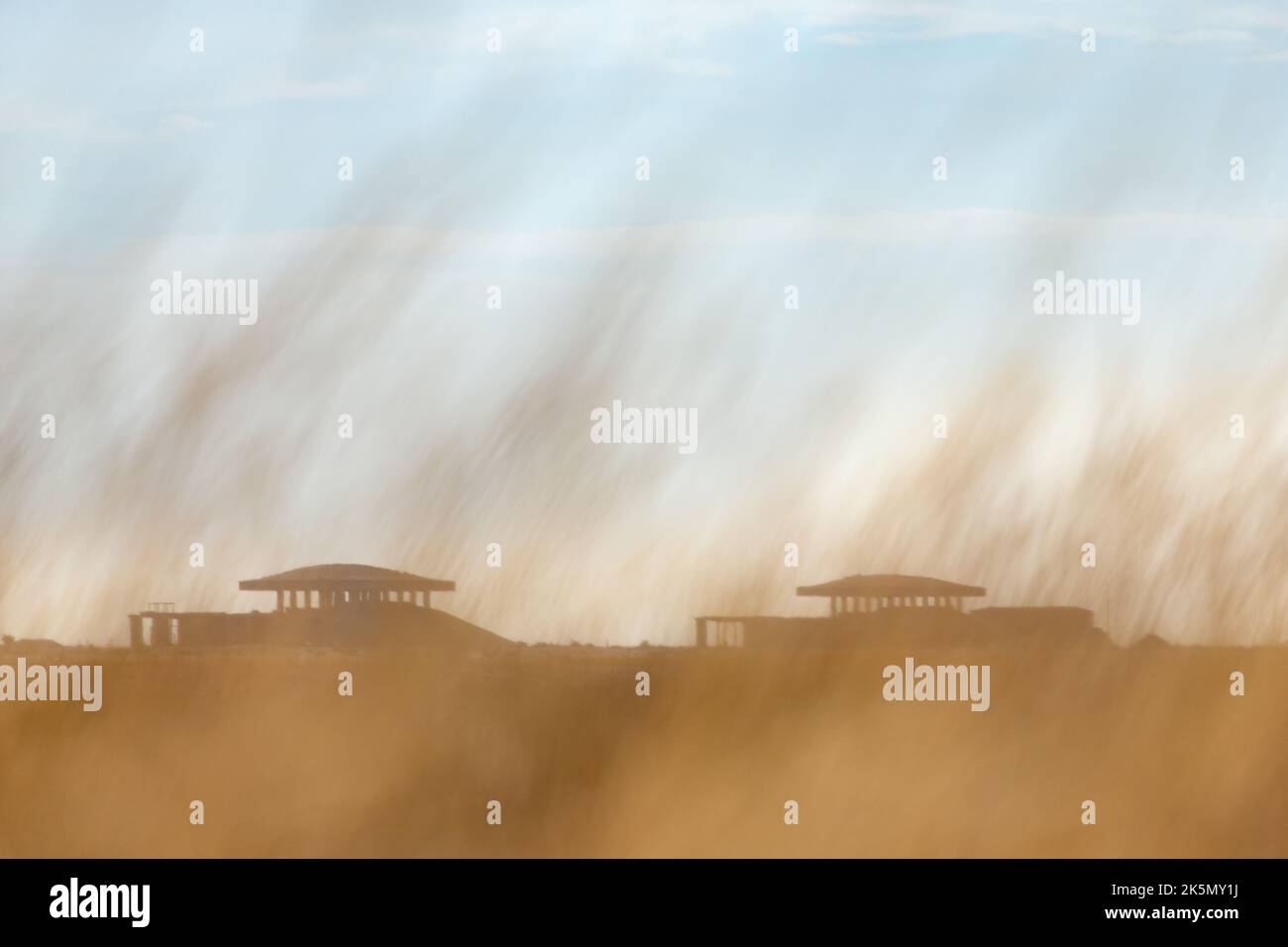 2 laboratorio di prova di munizioni atomiche 'Pagoda' strutture sagome dietro uno schermo di erba lunga che soffia nel vento. Orford Ness, Suffolk, Inghilterra Foto Stock