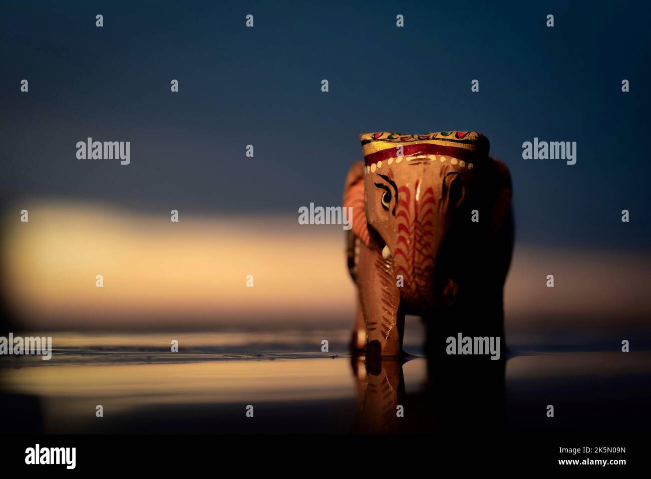 Un primo piano di una bella scultura di elefante in legno fatta a mano su una superficie scura Foto Stock