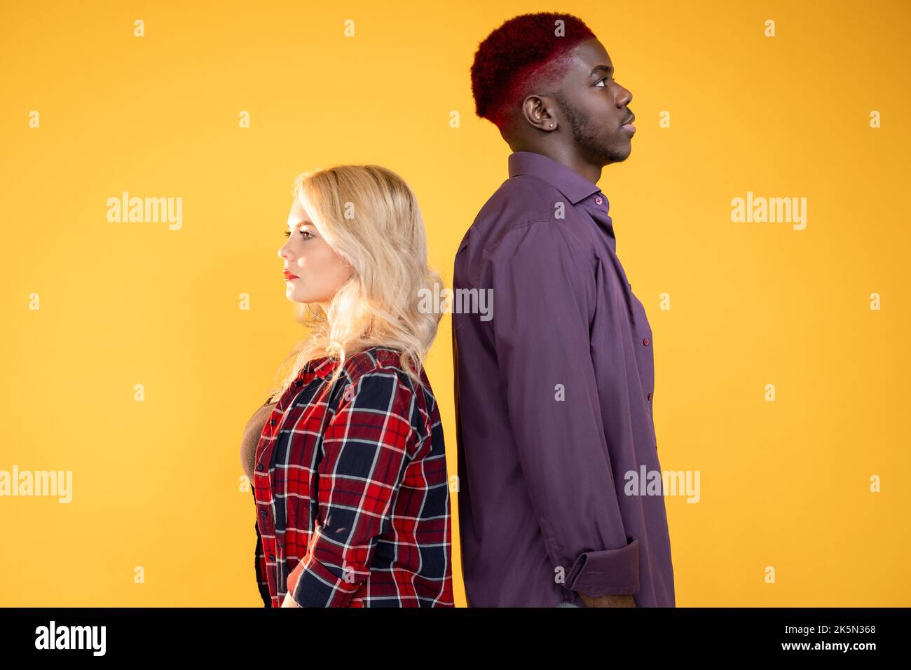 Diversità delle persone. Società multirazziale. Razza umana. Etnia diversa. Vista laterale di grave coppia multietnica uomo donna isolato su Be arancione brillante Foto Stock